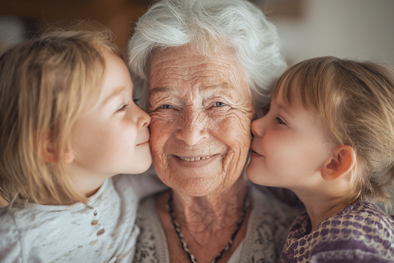 Grandkids kissing grandma's cheeks at The Parks at Garland Healthcare and Rehabilitation in Garland, TX
